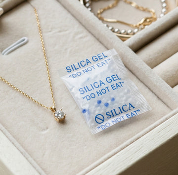 Gold necklace with a silica gel packet on a beige jewelry box