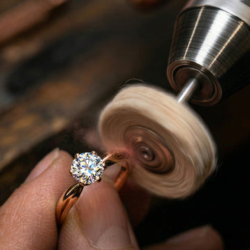Gold ring with a diamond being polished by a machine on a wooden surface